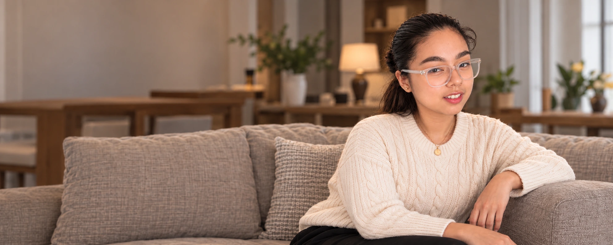 Jahnna Gloria in a cream sweater, seated on a sofa in a warm living room